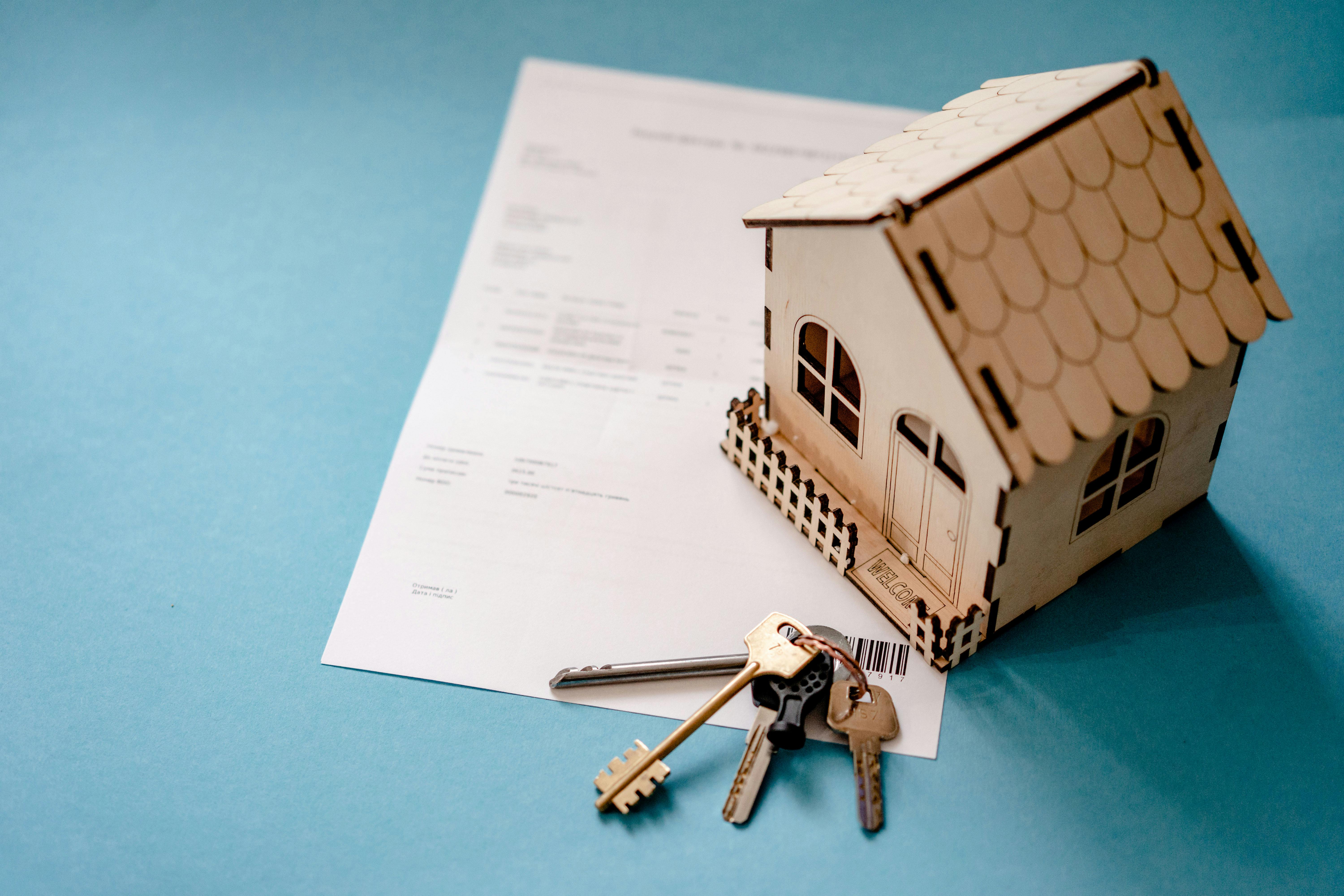A signed loan document placed beside a house model and a set of keys, representing successful disbursement of a property-backed loan through NBFCs and MFIs using Finpage's lending software.